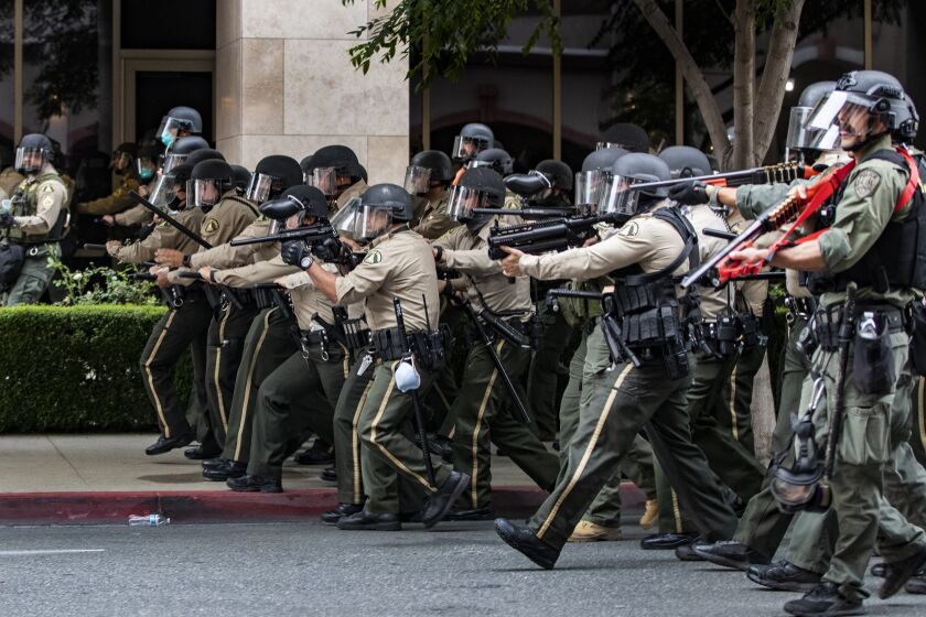 RIVERSIDE, CA - JUNE 1, 2020: Riverside County Sheriffs advance on demonstrators who refused to disperse after curfew during a protest against the death of George Floyd during the coronavirus pandemic on June 1, 2020 in Riverside, California. Thousands of protesters marched through the street of downtown Riverside and police alloyed them to stay 90 minutes after the 6pm curfew.