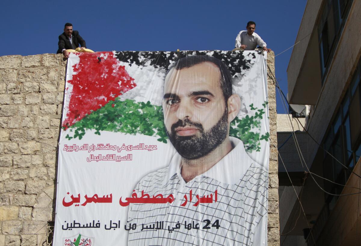 Palestinian relatives of prisoner Israr Samreen, who has been jailed by Israel, hang a poster that reads, "leader of prisoners in Ramallah, the heroic prisoner, Israr Mostafa Samreen, 24-year prisoner for Palestine." Samreen is expected to be among the prisoners released by Israel this week.