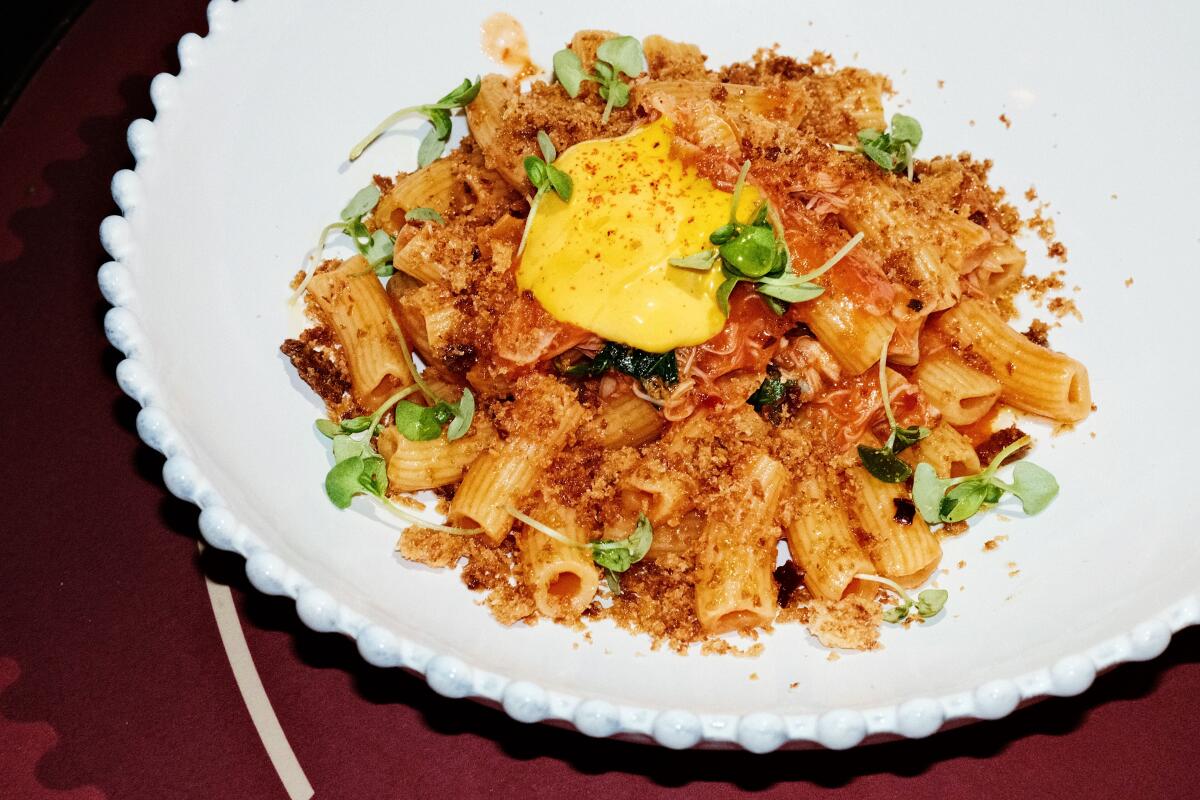 A white bowl of crab rigatoni pomodoro with saffron rouille and microgreens at Coucou West Hollywood