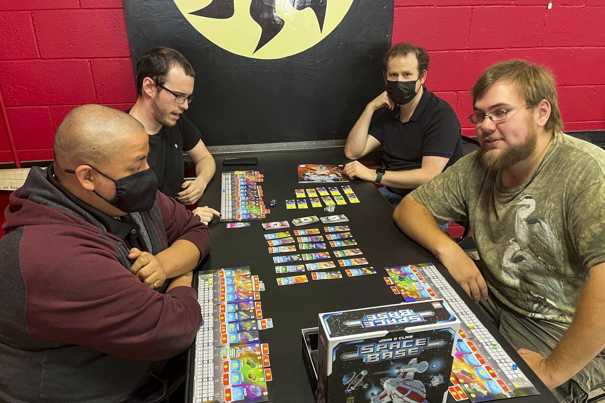 Four young men sit around a table playing a board game.