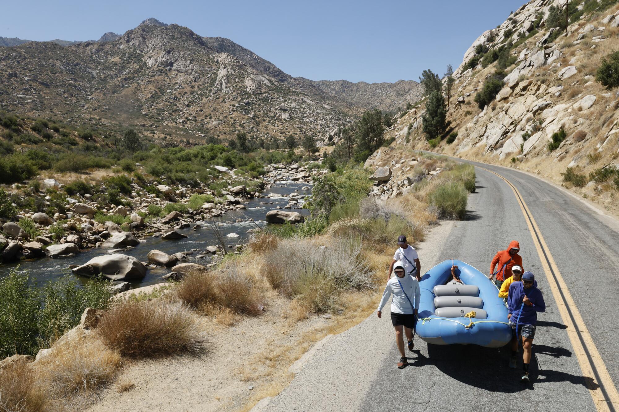 Rafters portage their raft on a road beside the Kern River.