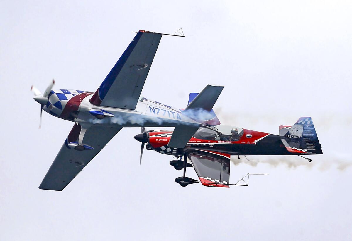 Pilots Sean Tucker and Rob Holland seem to touch wings as they perform in their stunt planes on Friday.