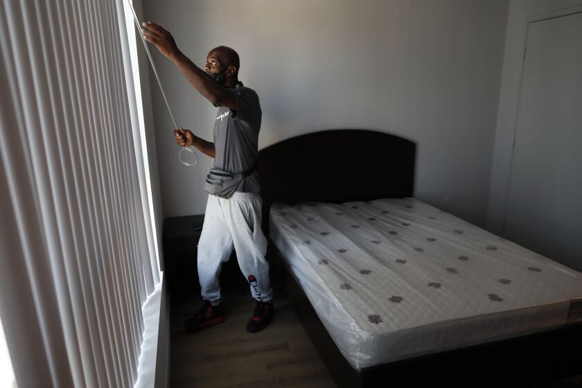 Los Angeles, CA, August 12, 2022 - Donald Winston adjusts blinds moments after moving into his new apartment. (Robert Gauthier/Los Angeles Times)