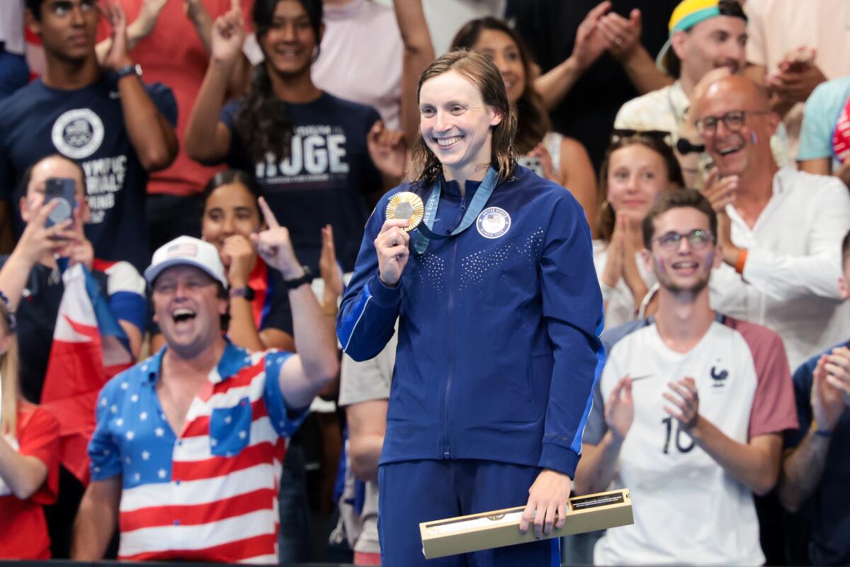 Katie Ledecky holds up her gold medal after winning the women's 1,500-meter swimming final.