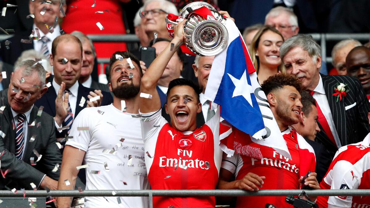 Alexis Sanchez lifts the FA Cup trophy as Arsenal players celebrate their victory over Chelsea in the championship match Saturday.