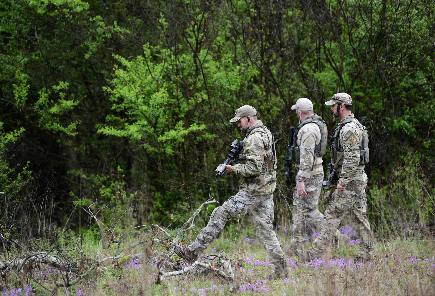 Bureau of Alcohol, Tobacco, Firearms and Explosives personnel search a wooded area Monday for the suspect who shot and killed several people in a nearby Waffle House in Nashville.