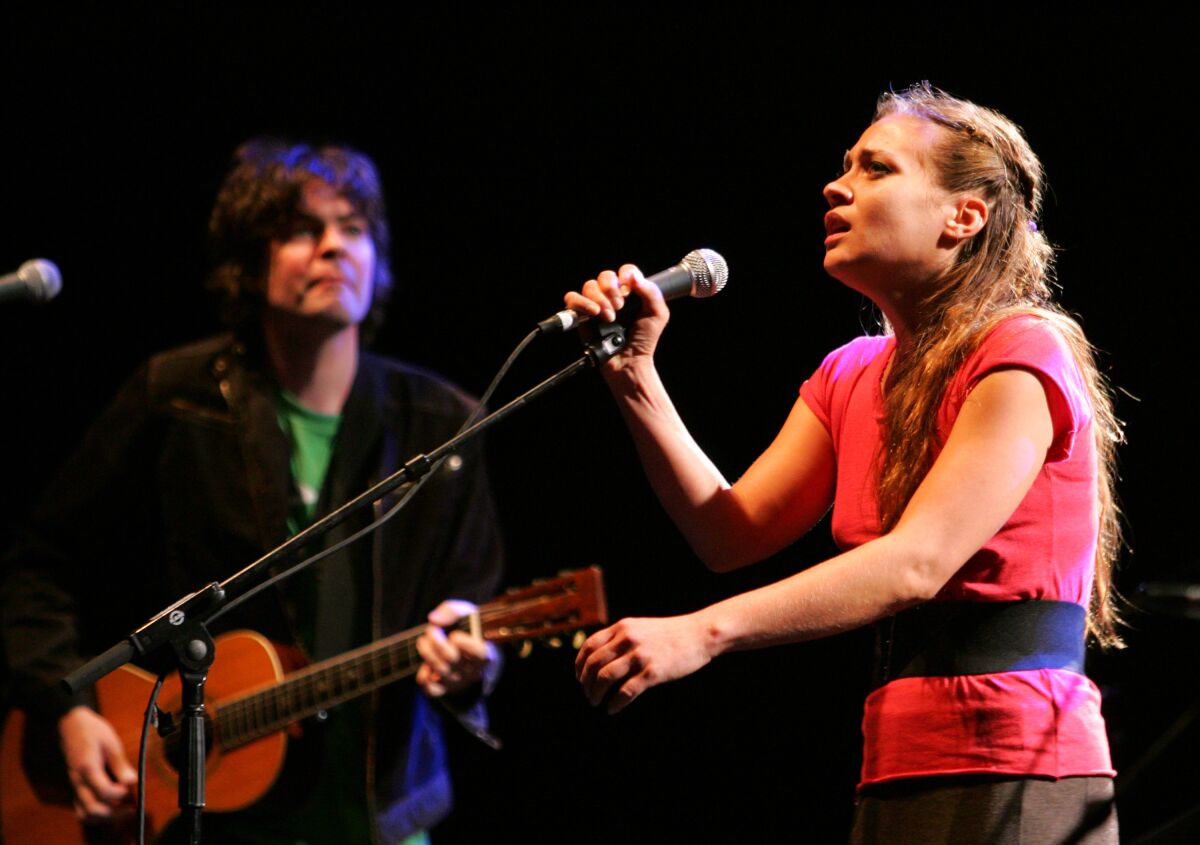 A male guitarist and female singer perform onstage