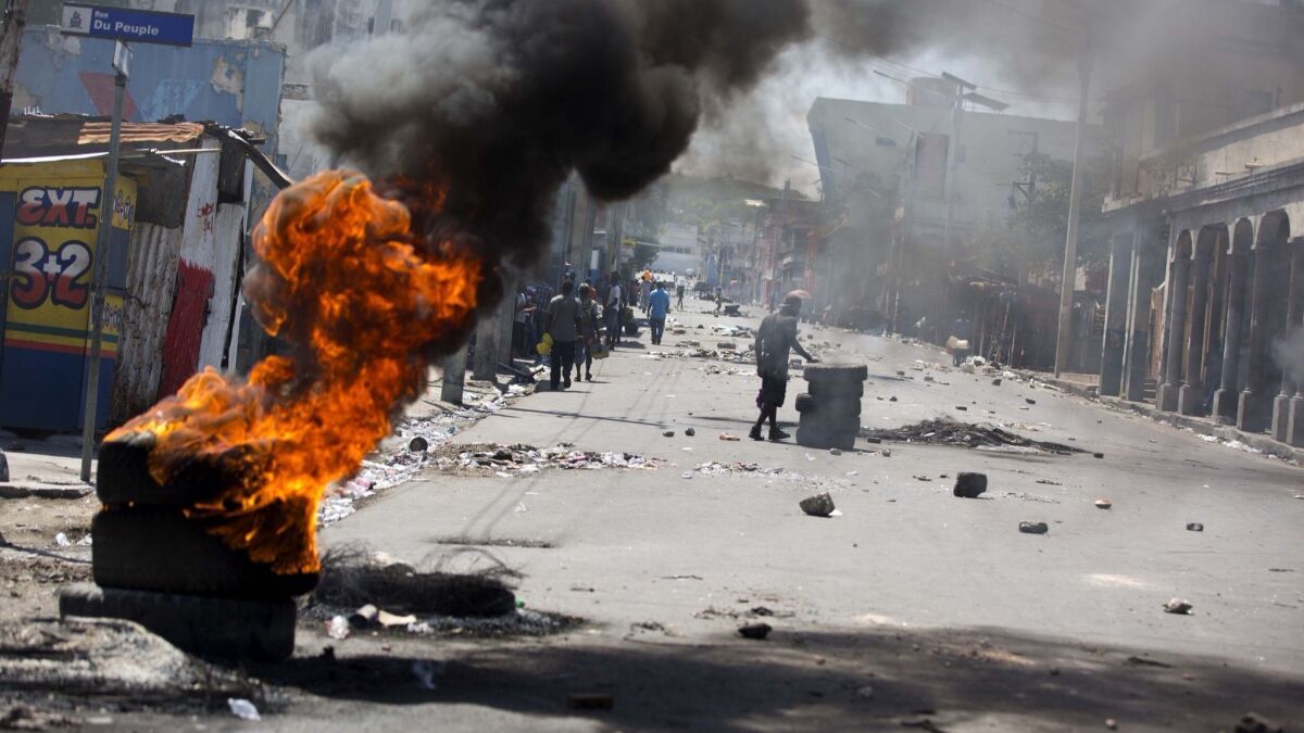 Tires burn at a road block set up by anti-government protesters downtown during a general strike in Port-au-Prince, Haiti, early Monday, July 9, 2018.