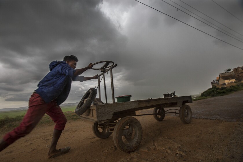 In this photo taken Monday, Dec. 9, 2019 a street vendor makes his way home under stormy skies in Antananarivo, Madagascar. Officials said Tuesday that Cyclone Belna has hit northern Madagascar, killing nine people and making more then 1,400 homeless. (AP Photo/Alexander Joe)