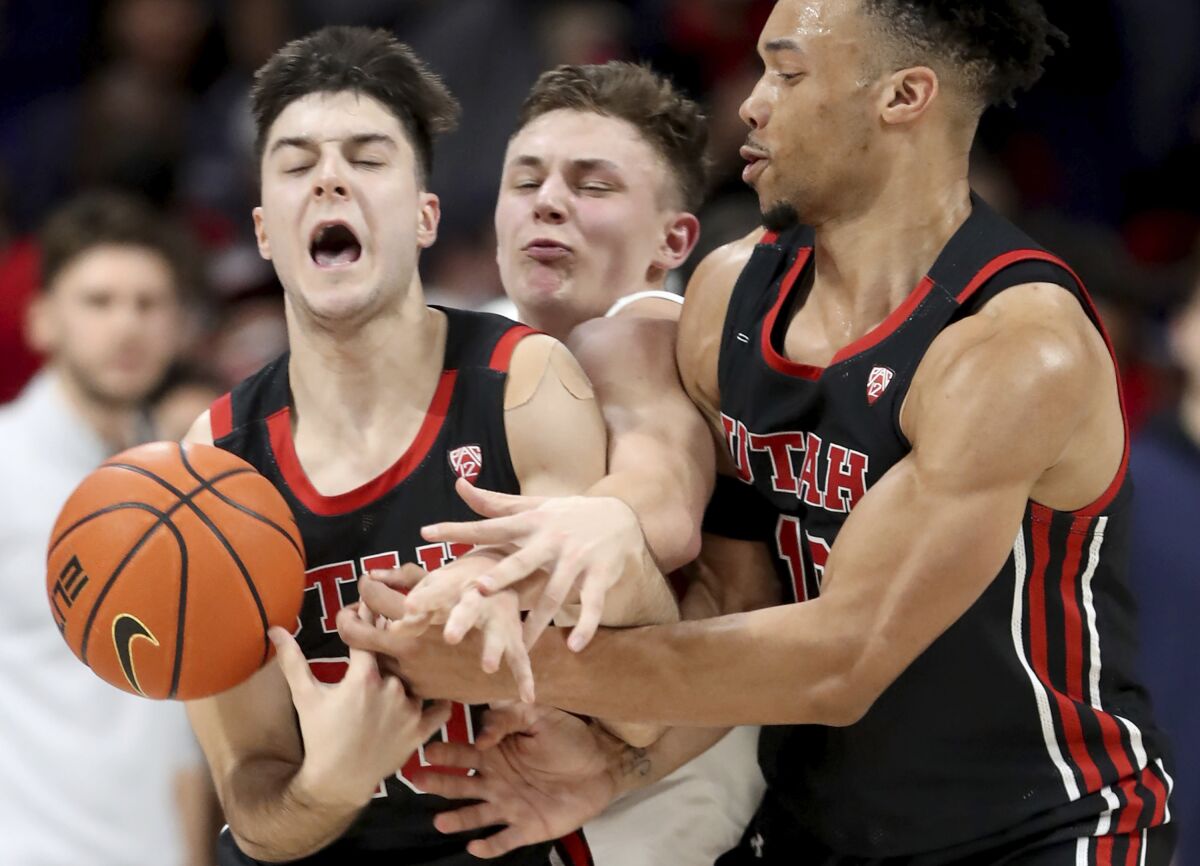 Arizona guard Pelle Larsson, center, is squeezed between Utah guards Lazar Stefanovic, left, and Marco Anthony, right, while fighting through a pick in the first half of an NCAA college basketball game in Tucson, Ariz., Saturday, Jan. 15, 2022. (Kelly Presnell/Arizona Daily Star via AP)