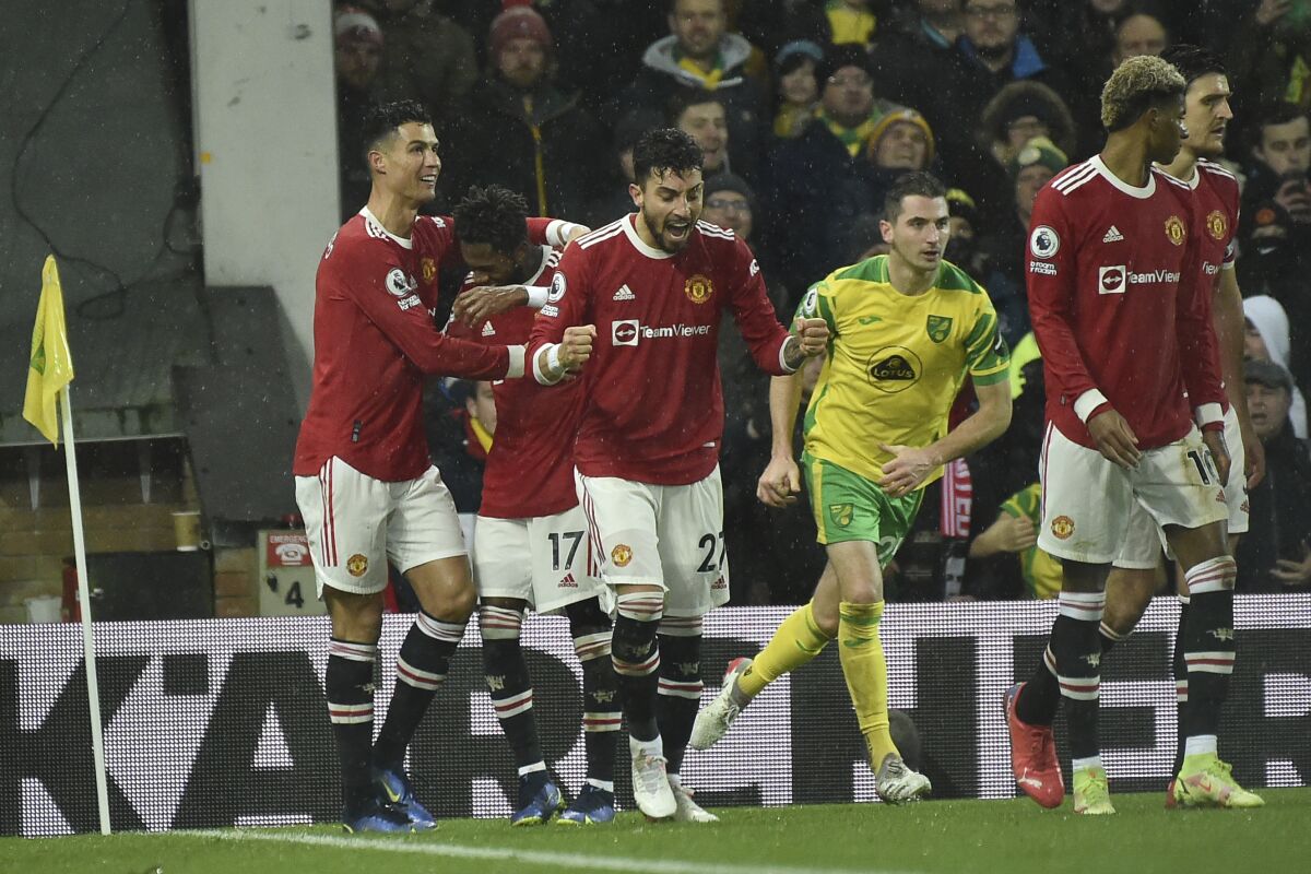 Manchester United's Cristiano Ronaldo, left, celebrates with Fred, 2nd left and Alex Telles, 3rd left after scoring the opening goal from a penalty kick during the English Premier League soccer match between Norwich City and Manchester United at Carrow road in Norwich, England, Saturday, Dec.11, 2021. (AP Photo/Rui Vieira)