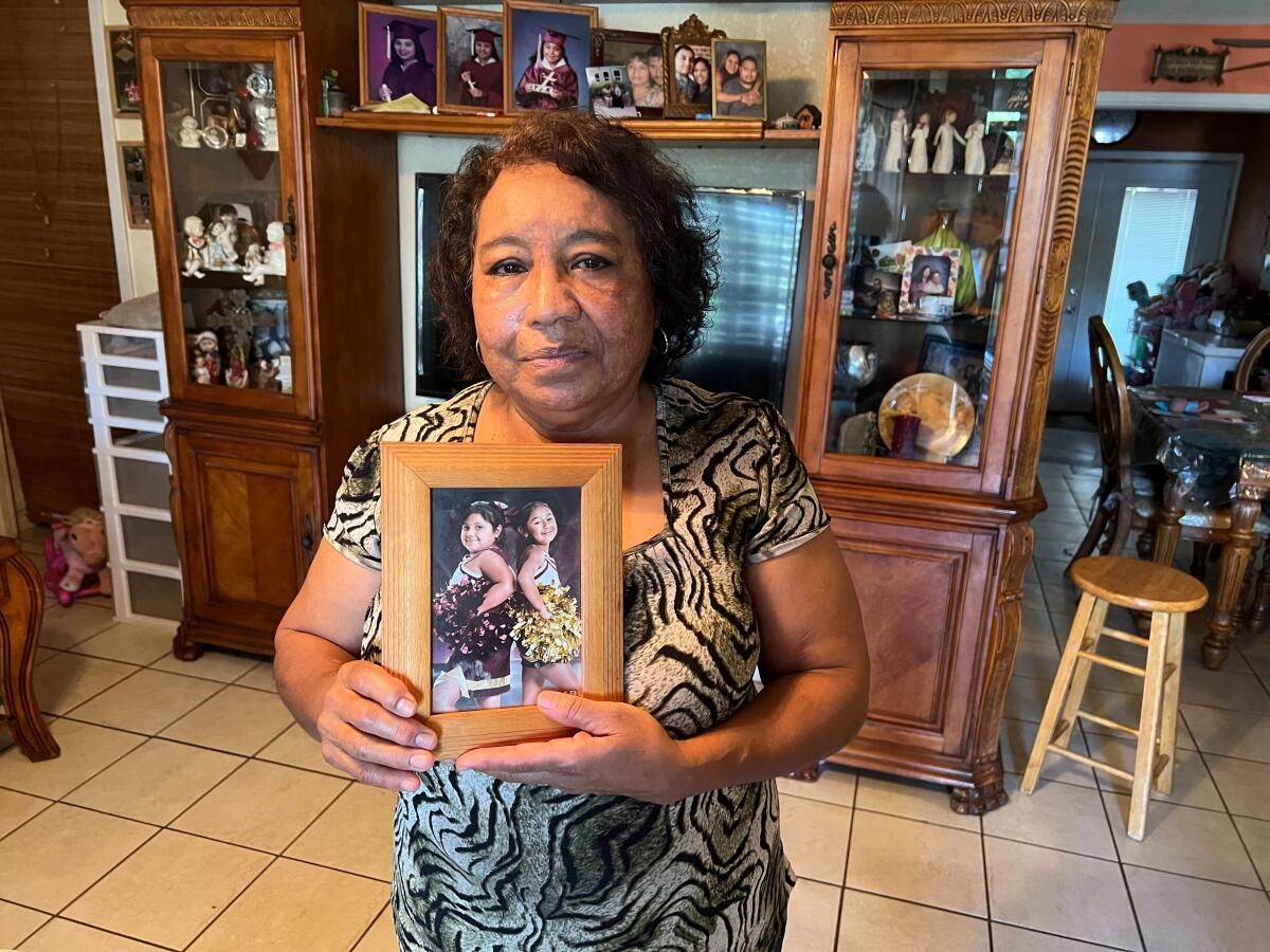 Woman holding framed photo of two granddaughters.