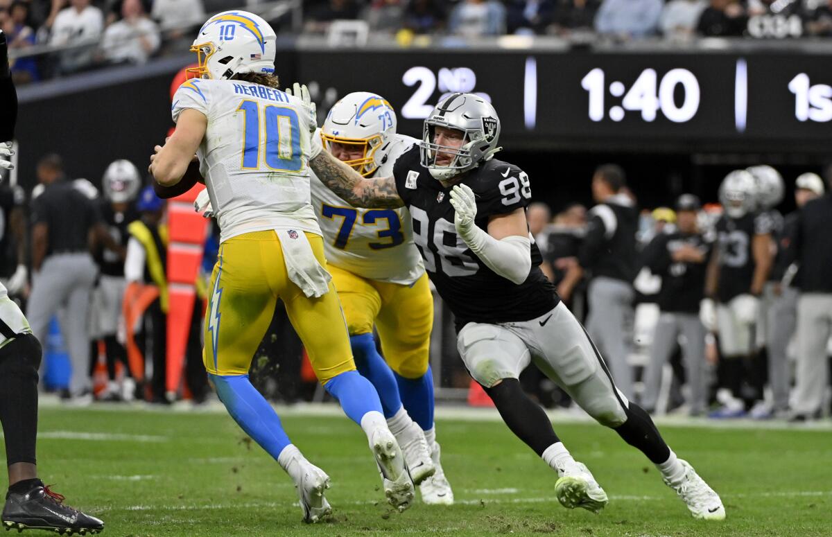 Raiders defensive end Maxx Crosby (98) closes on Chargers quarterback Justin Herbert (10).  