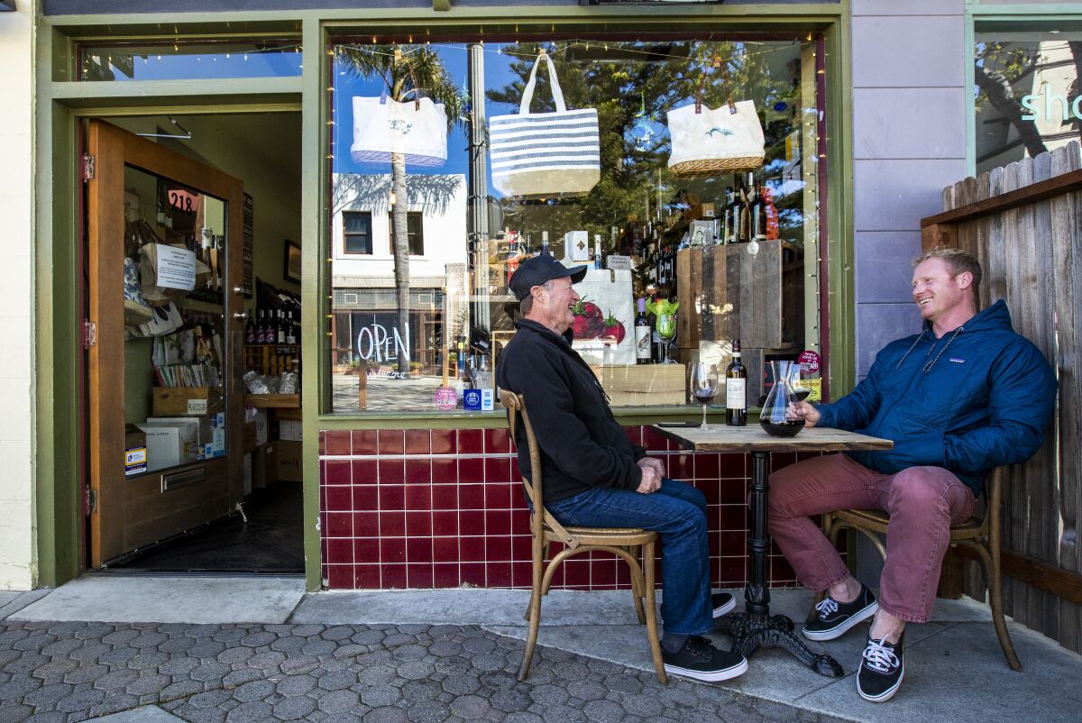 Tomas Mercer, left, and Jonathan Mercer, right, enjoy a bottle of wine outside Paradise Pantry on Main St. in Ventura.