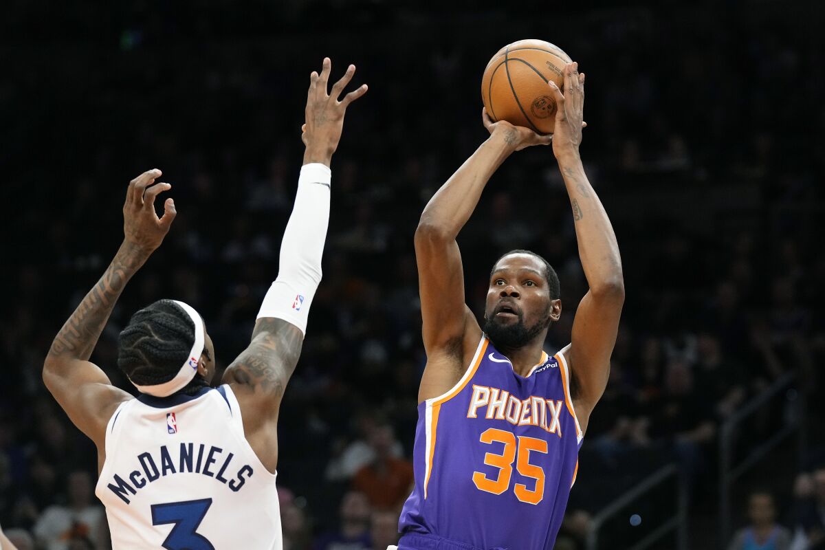 Kevin Durant, alero de los Suns de Phoenix, dispara frente a Jaden McDaniels, de los Timberwolves de Minnesota, el miércoles 29 de marzo de 2023 (AP Foto/Ross D. Franklin)