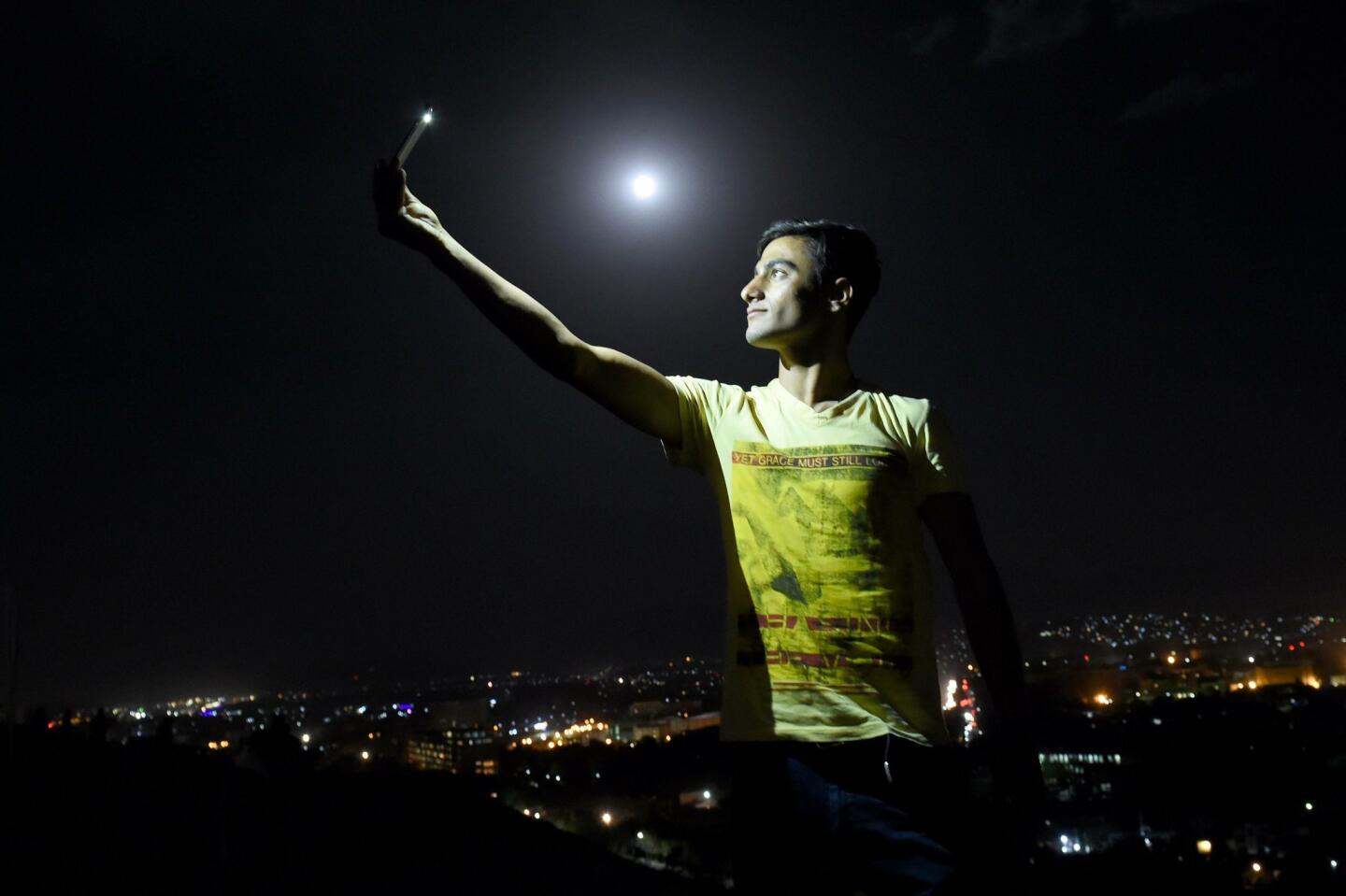 An Afghan man is illuminated by the light from his phone while taking a selfie on the top of the Wazir Akbar Khan hill in Kabul.