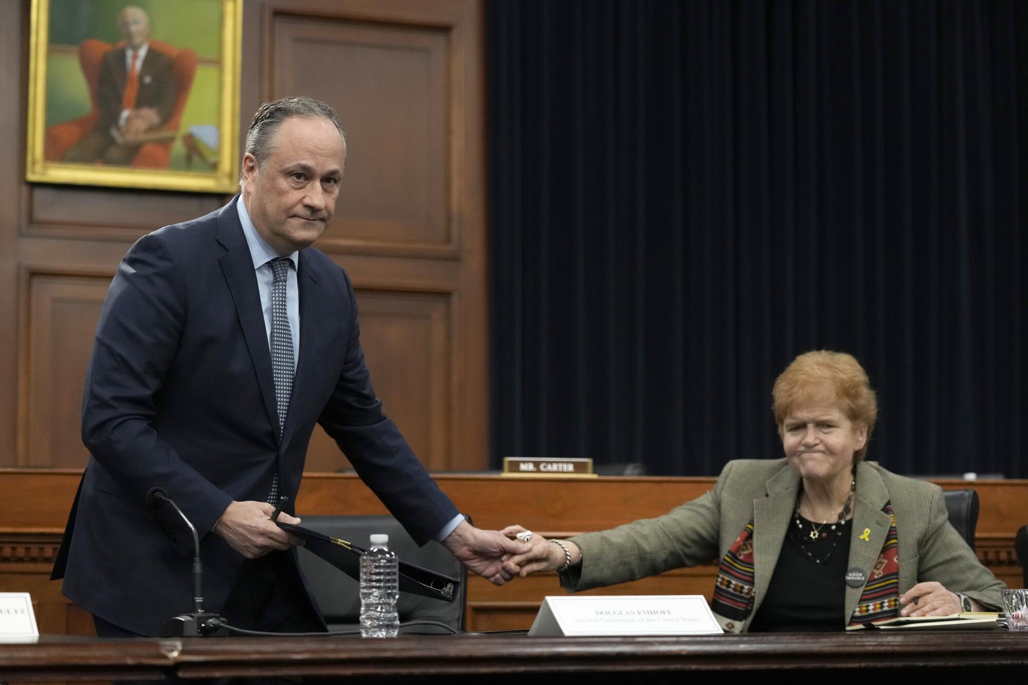 Second gentleman Doug Emhoff, left, and Deborah Lipstadt shake hands at a table.