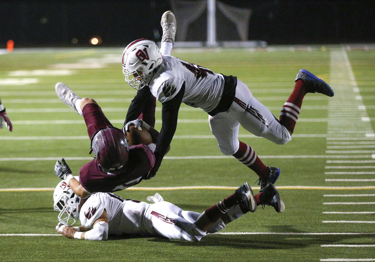 Wyatt Bogdan (17) of Laguna Beach is brought down hard by two defenders including Gaige Prichard, right, Friday's game.