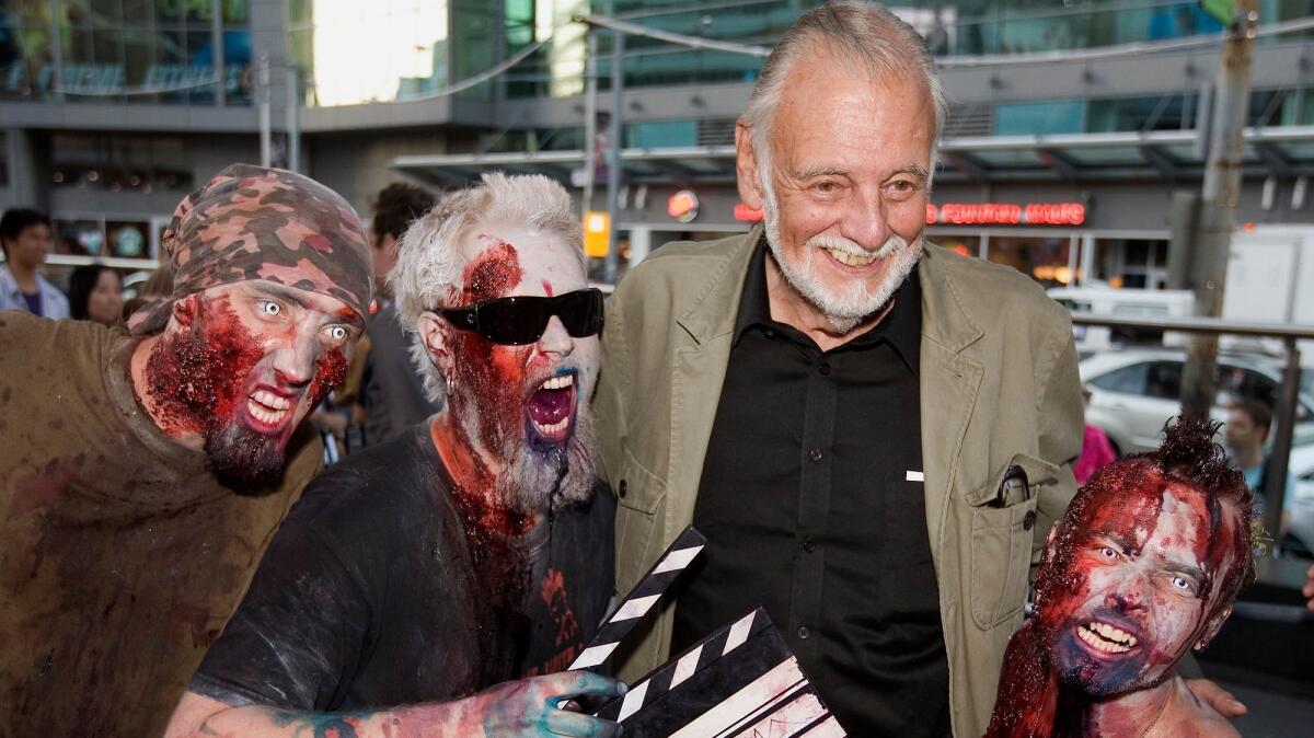 Director George Romero poses with fans dressed as zombies during the Toronto International Film Festival in Toronto on Sept. 12, 2009. Romero died on Sunday at the age of 77.