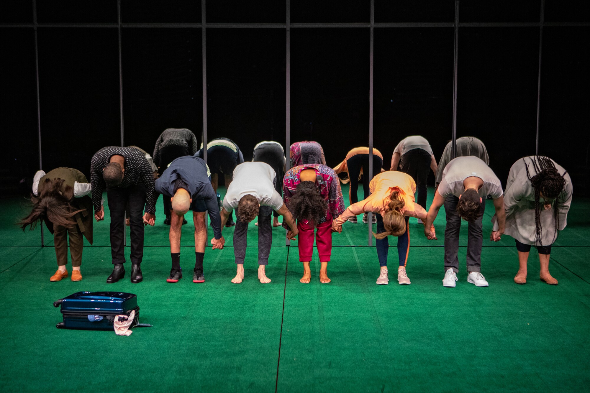 In front of a mirrored backdrop, the cast of "Slave Play" links hands and bows.