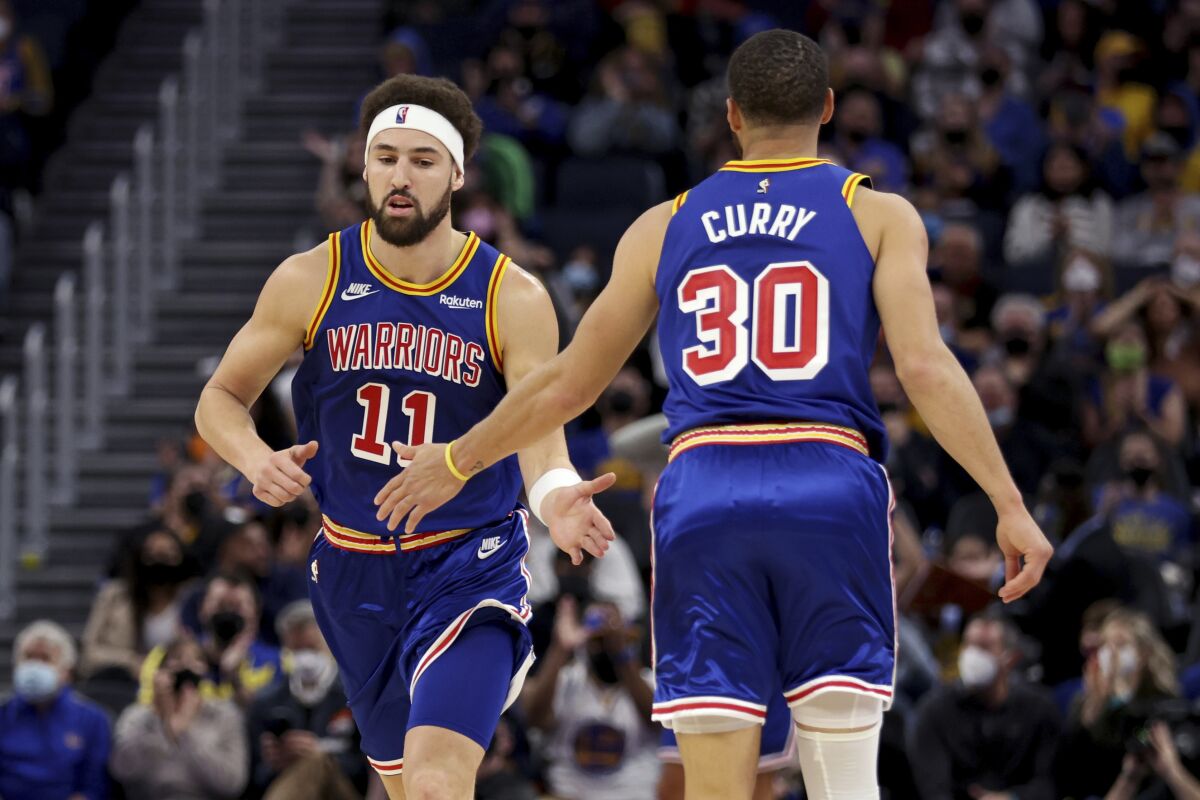 Golden State Warriors guard Klay Thompson (11) is congratulated by guard Stephen Curry (30) after Thompson scored against the Detroit Pistons during the first half of an NBA basketball game in San Francisco, Tuesday, Jan. 18, 2022. (AP Photo/Jed Jacobsohn)