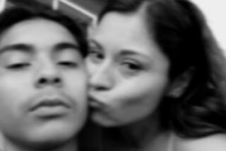 A blurry black-and-white selfie photo of a teenaged boy and a woman kissing his cheek