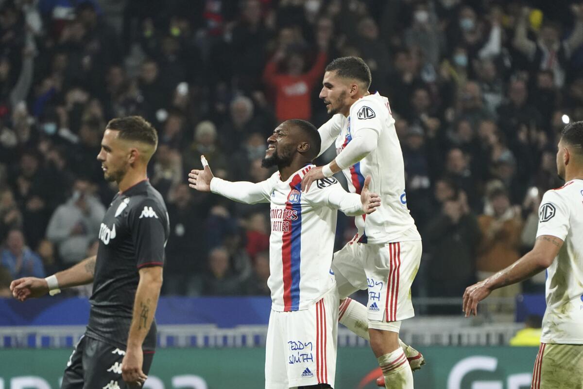 Lyon's Karl Toko Ekambi, center, celebrates with Lyon's Houssem Aouar, top, after scoring against Monaco during the French League One soccer match between Lyon and Monaco at the Groupama stadium in Lyon, France, Saturday, Oct. 16, 2021. (AP Photo/Laurent Cipriani)