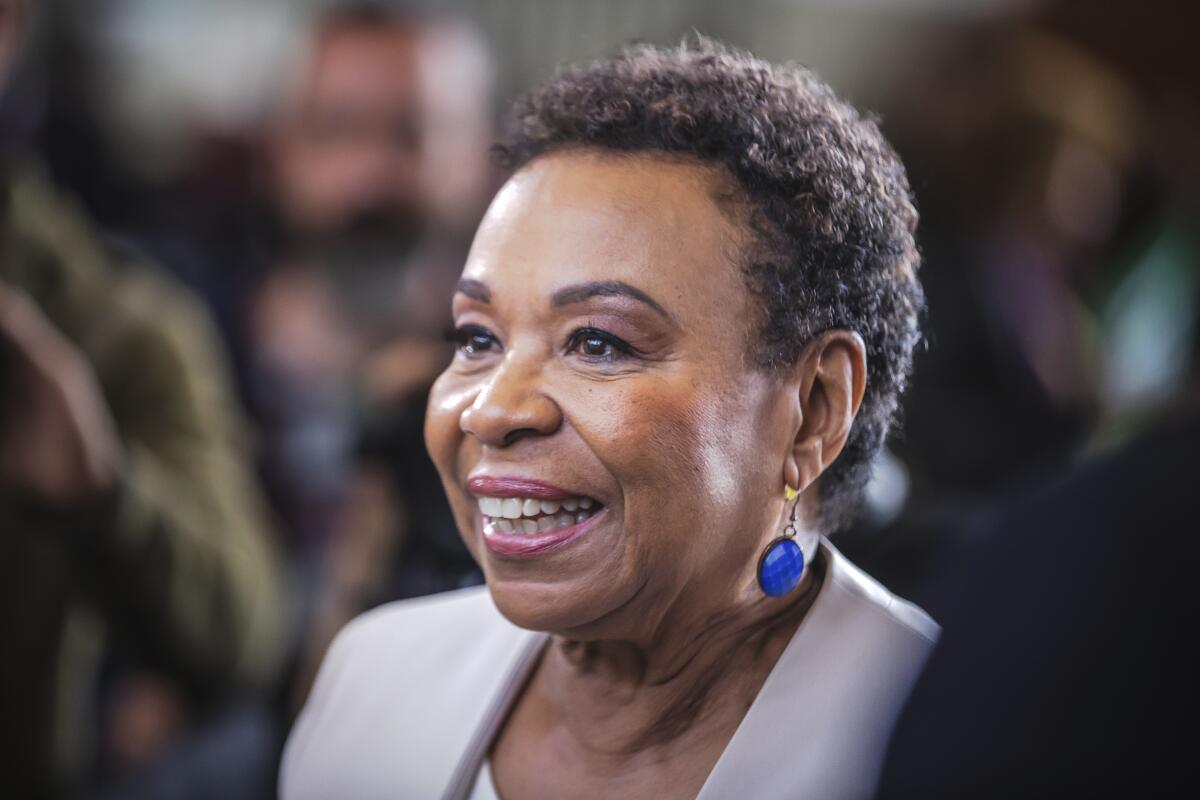 Rep. Barbara Lee of Oakland smiling in three-quarter profile among a crowd of people