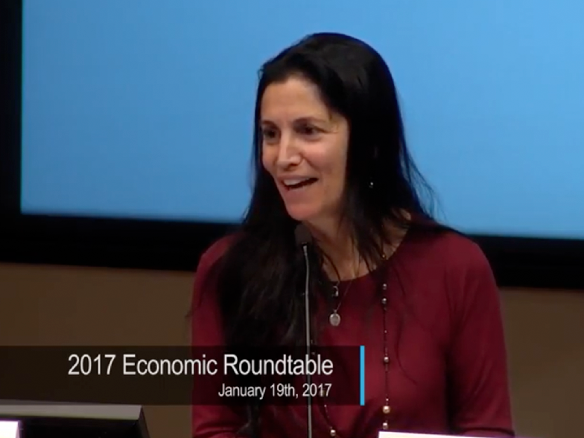 A screenshot of Gina Champion-Cain speaking at the 2017 San Diego Economic Roundtable panel at the University of San Diego.