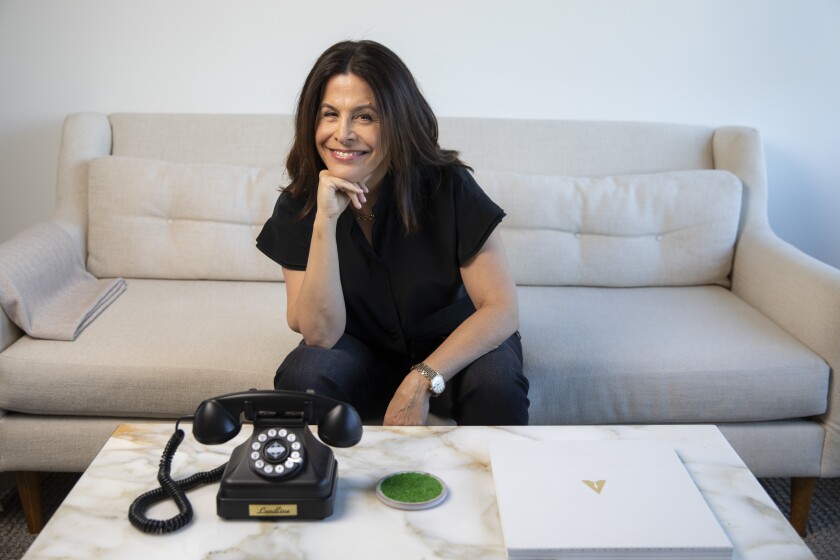 Film producer Amy Baer sits on a couch with an old-fashioned dial telephone.