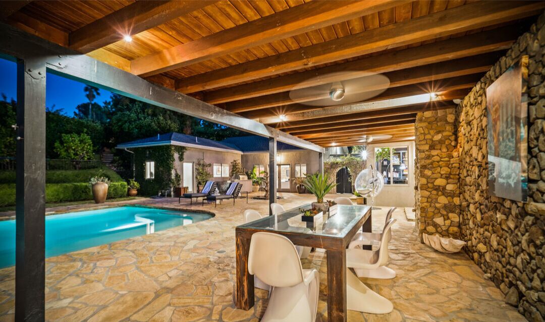 The dining patio has an overhang from the house plus furniture next to the pool.