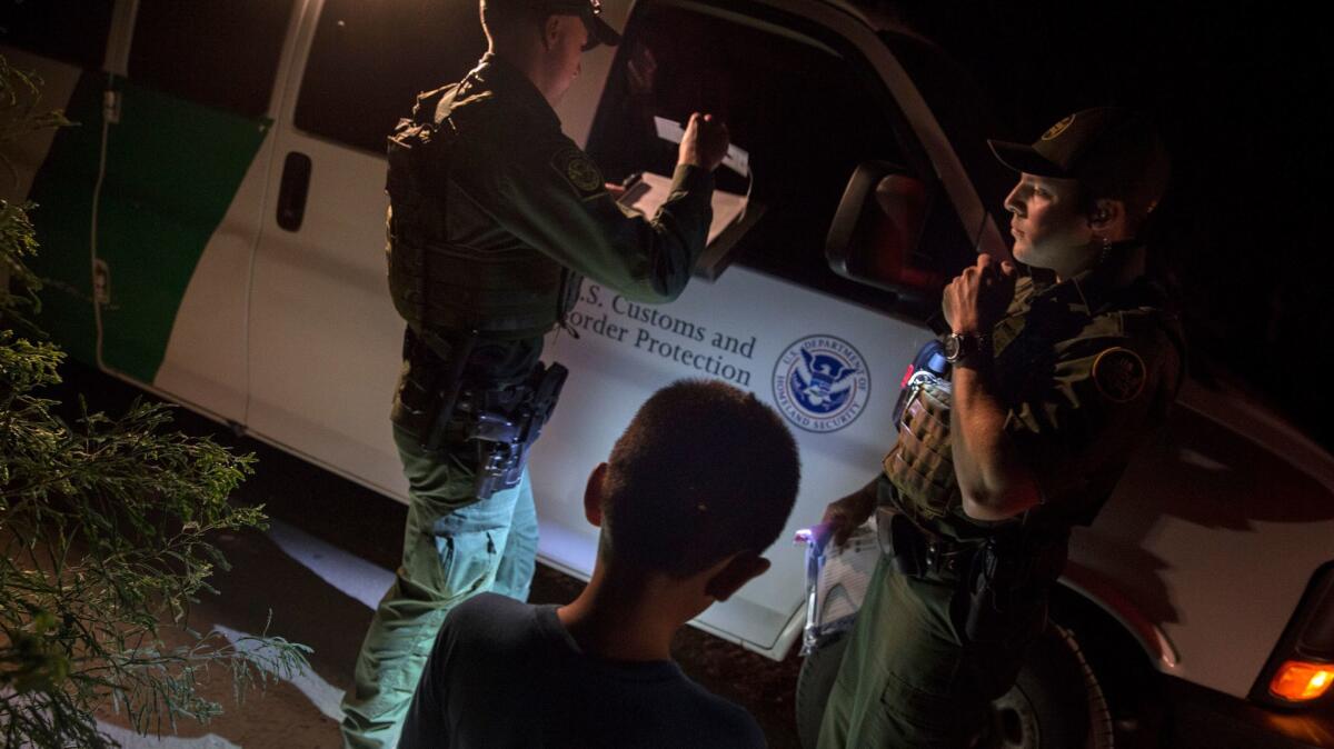 Border Patrol agents process an unaccompanied minor for transportation after the boy illegally crossed the Rio Grande on a raft in Hidalgo, Texas.