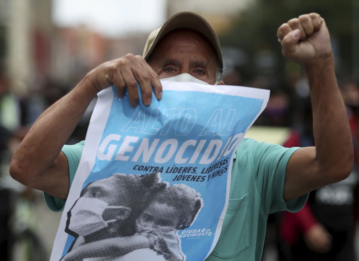 A protester holds a poster with a message that reads in Spanish: "Stop the Genocide," during a demonstration against a wave of massacres, in Bogota, Colombia, Monday, Sept. 21, 2020. Rather than a national dispute between guerrillas and the state, violence in rural Colombia is now marked by a patchwork of local feuds between criminal groups who fight over drug routes, illegal mines and even gasoline smuggling routes. (AP Photo/Fernando Vergara)