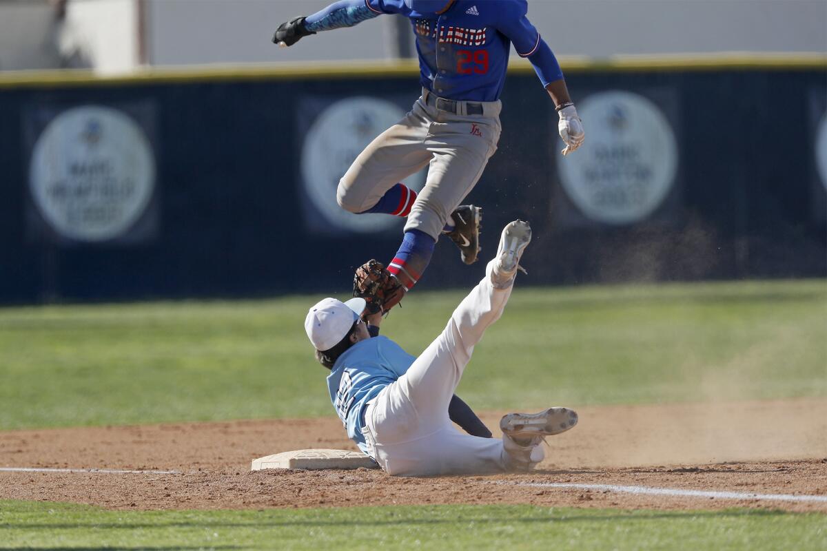 Marina's Jake Sellers, bottom, makes the tag on Los Alamitos' Zech Samayoa (29) at third base during the third inning of a Sunset Conference crossover game in Huntington Beach on Wednesday.