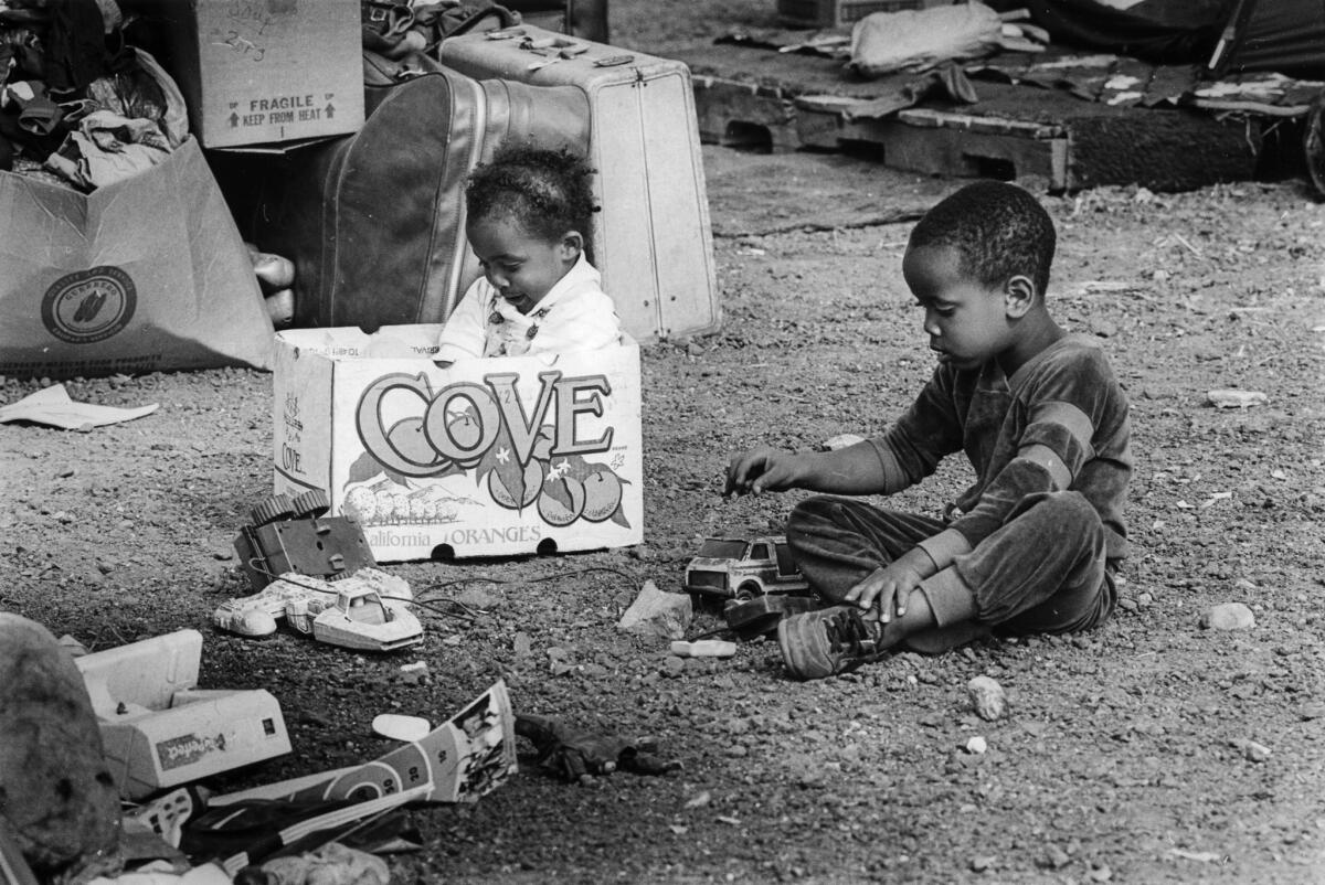 June 26, 1987: Two children play with toys and an empty box at the encampment.
