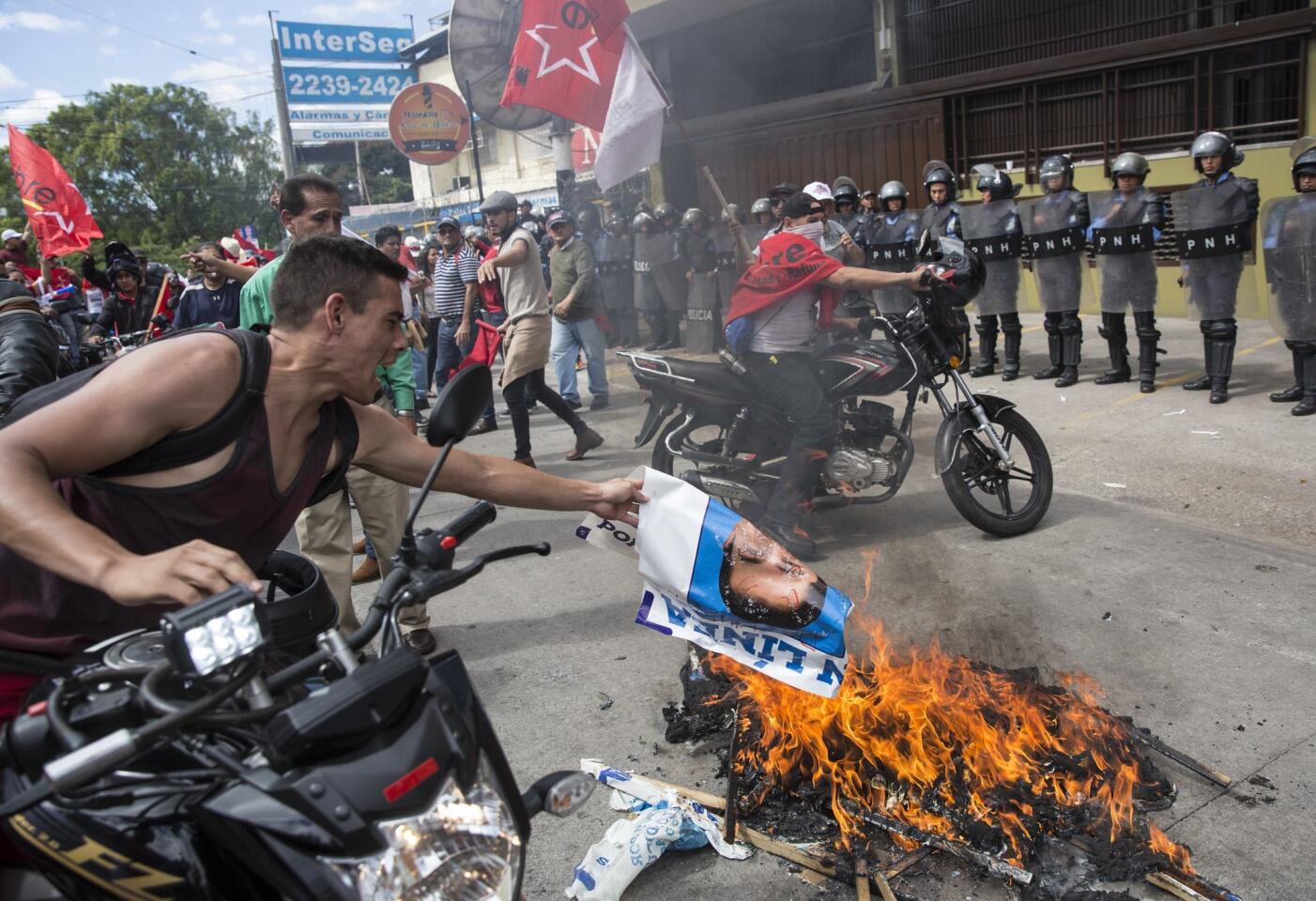 A supporter of Libre Alliance presidential candidate Salvador Nasralla adds to a bonfire of burning banners promoting Honduran President Juan Orlando Hernandez during a protest claiming electoral fraud outside the Supreme Electoral Tribunal in Tegucigalpa, Honduras.