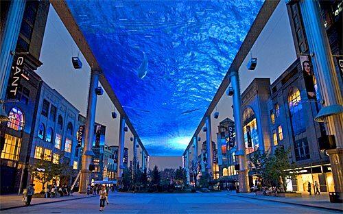 A gigantic video screen dwarfs shoppers at the Place in Beijing's Central Business District, which was the focus of an Olympics update. Many of the Olympics organizers are working on preparations for for the 60th anniversary celebrations of the Communist revolution in October.