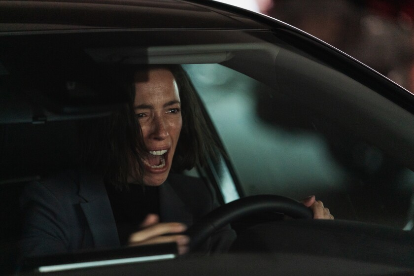 A woman screams in the driver's seat of a car.