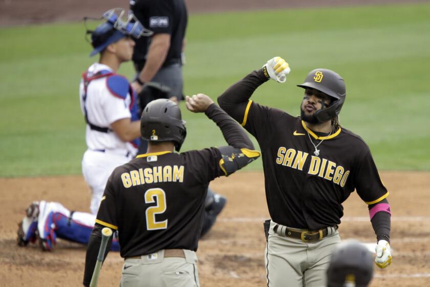 San Diego Padres' Fernando Tatis Jr., right, celebrates his solo home run with Trent Grisham as Los Angeles Dodgers catcher Austin Barnes, above left, looks away during the fourth inning of a baseball game in Los Angeles, Sunday, April 25, 2021. (AP Photo/Alex Gallardo)