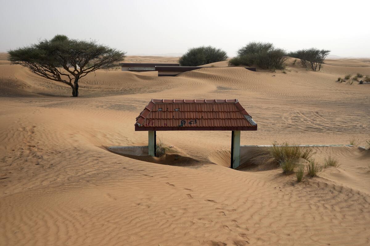 A house's entrance gate is buried under the sand at the Bedouin village of Al-Ghuraif, United Arab Emirates.