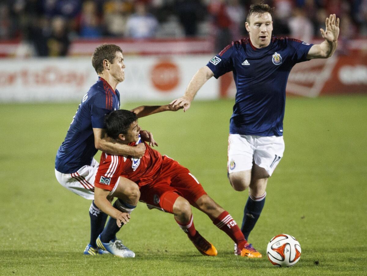 Chivas USA's Thomas McNamara, right, goes for the ball as his teammate Tony Lockhead, left, pulls down FC Dallas' Mauro Diaz during a match on March 22 at Toyota Stadium.
