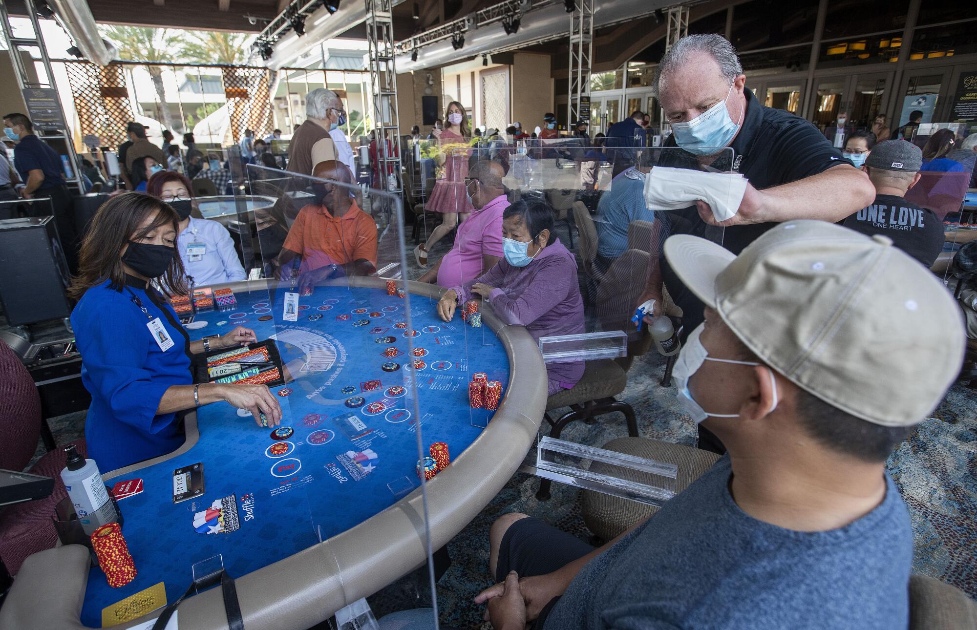 Craig Phillips sanitizes a plexiglass partition between gamblers at Gardens Casino.