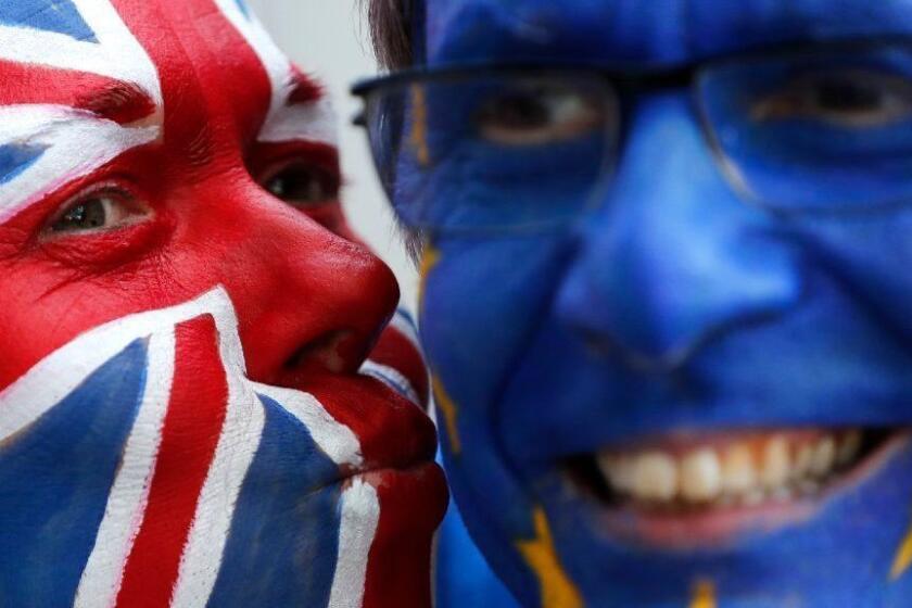 FILE - In this Thursday, March 21, 2019 file photo, activists pose with their faces painted in the EU and Union Flag colors during an anti-Brexit campaign stunt outside EU headquarters during an EU summit in Brussels. The country's struggle to leave the European Union is one of the great political crisis to afflict Britain in the postwar period. (AP Photo/Frank Augstein, File)