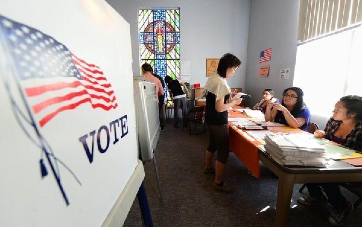 A voter receives instructions before casting her ballot at a polling station at St. Paul's Lutheran Church in Monterey Park.