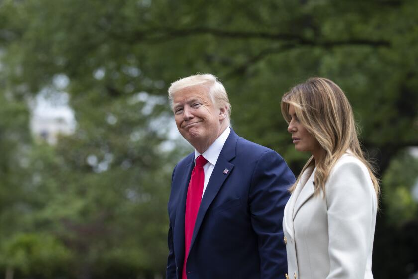 President Donald Trump, accompanied by first lady Melania Trump, smiles while walking as they return on Marine One on the South Lawn of the White House, Monday, May 25, 2020, in Washington. Trump is returning from Fort McHenry National Monument and Historic Shrine, in Baltimore, for a Memorial Day ceremony. (AP Photo/Alex Brandon)