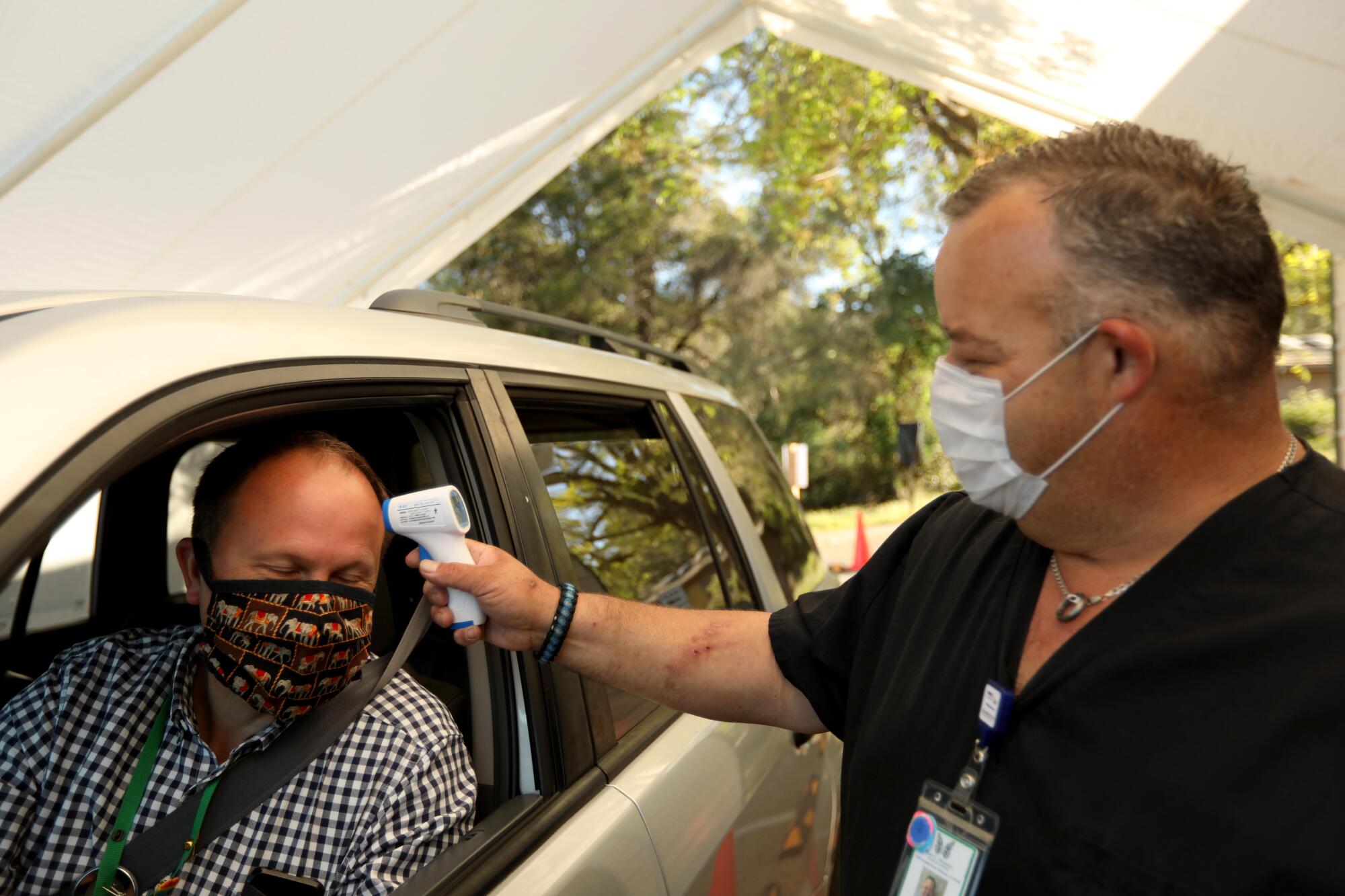 Matthew Matthiessen, CEO of John C. Fremont Hospital, has his temperature taken