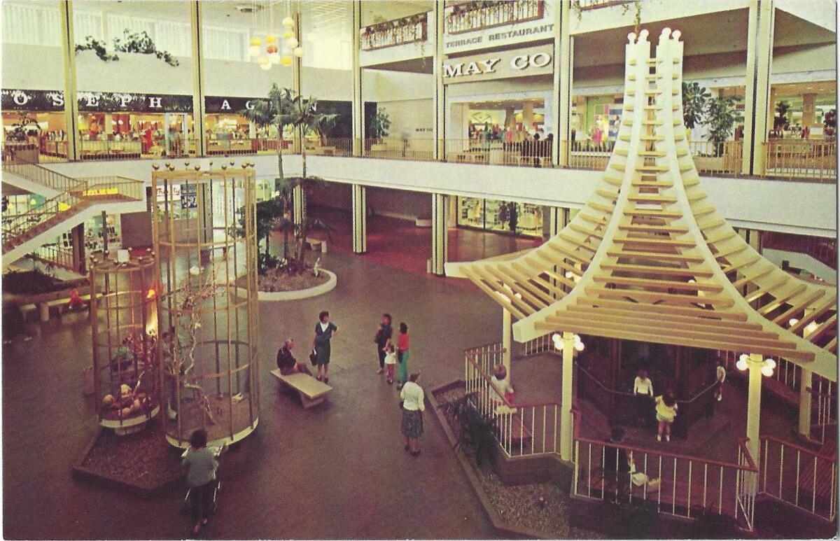 A May Company sign is visible in this interior mall scene on a vintage postcard.