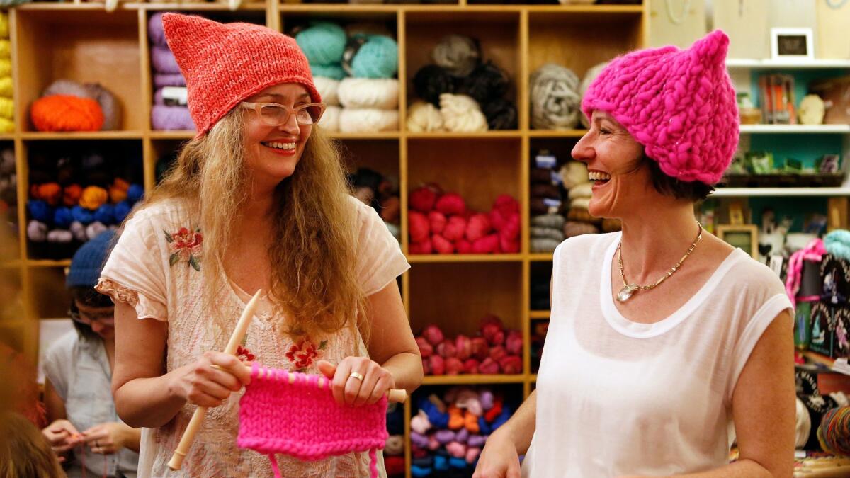 Kat Coyle, left, owner of the Little Knittery in Atwater Village, shares a laugh with Megan Hollingshead, while teaching her how to knit a "pussyhat" like the ones they are wearing.