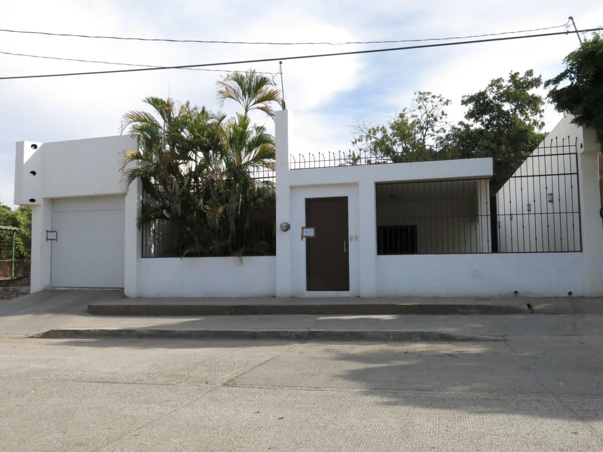 A low-slung white building with a gate