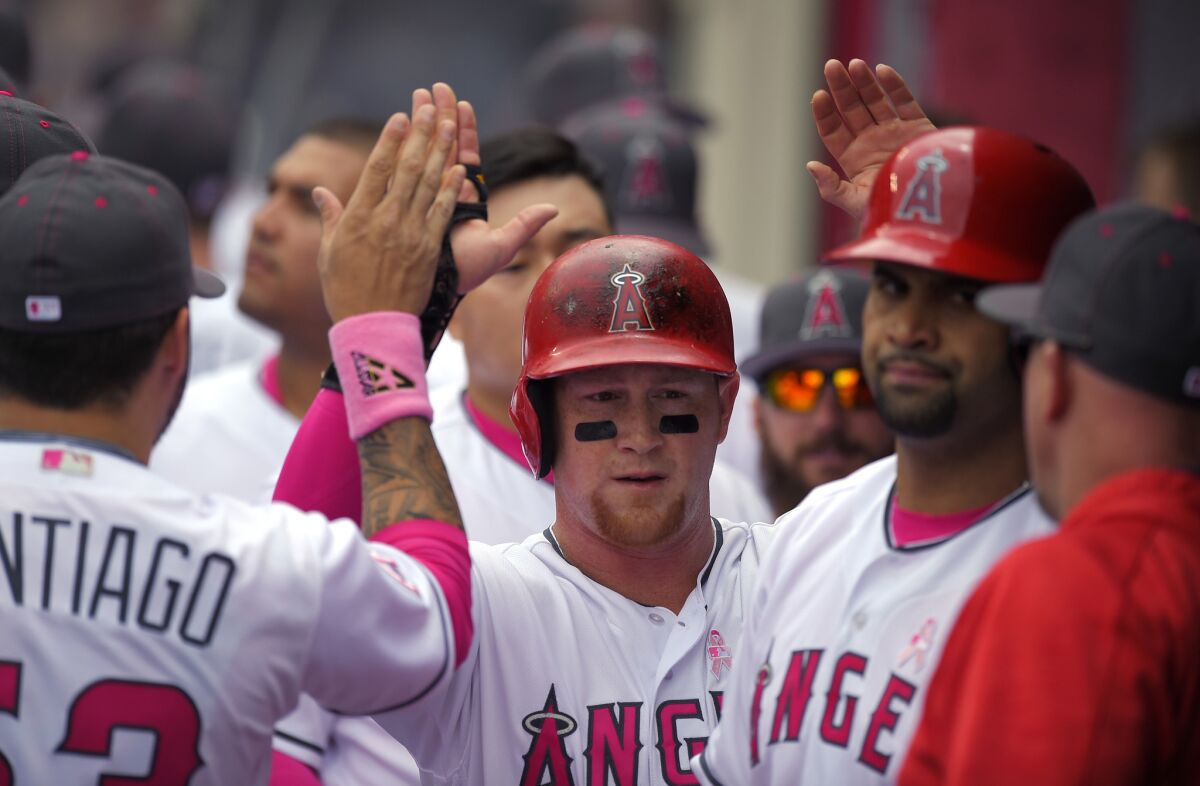 Angels outfielder Kole Calhoun, center, is congratulated by teammates after scoring on a sacrifice fly hit by Albert Pujols during the first inning.